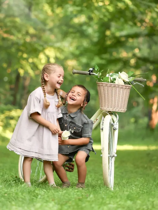 Brother and sister laughing by a bicycle with a flower basket, outdoor photography by Photoholic, Rockland County NY