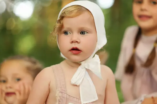Baby in a white bonnet with her sisters, outdoor photography by Photoholic, Rockland County NY